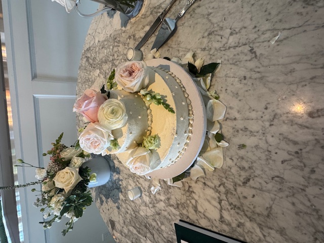 Two-tier ivory cake with roses on a marble counter
