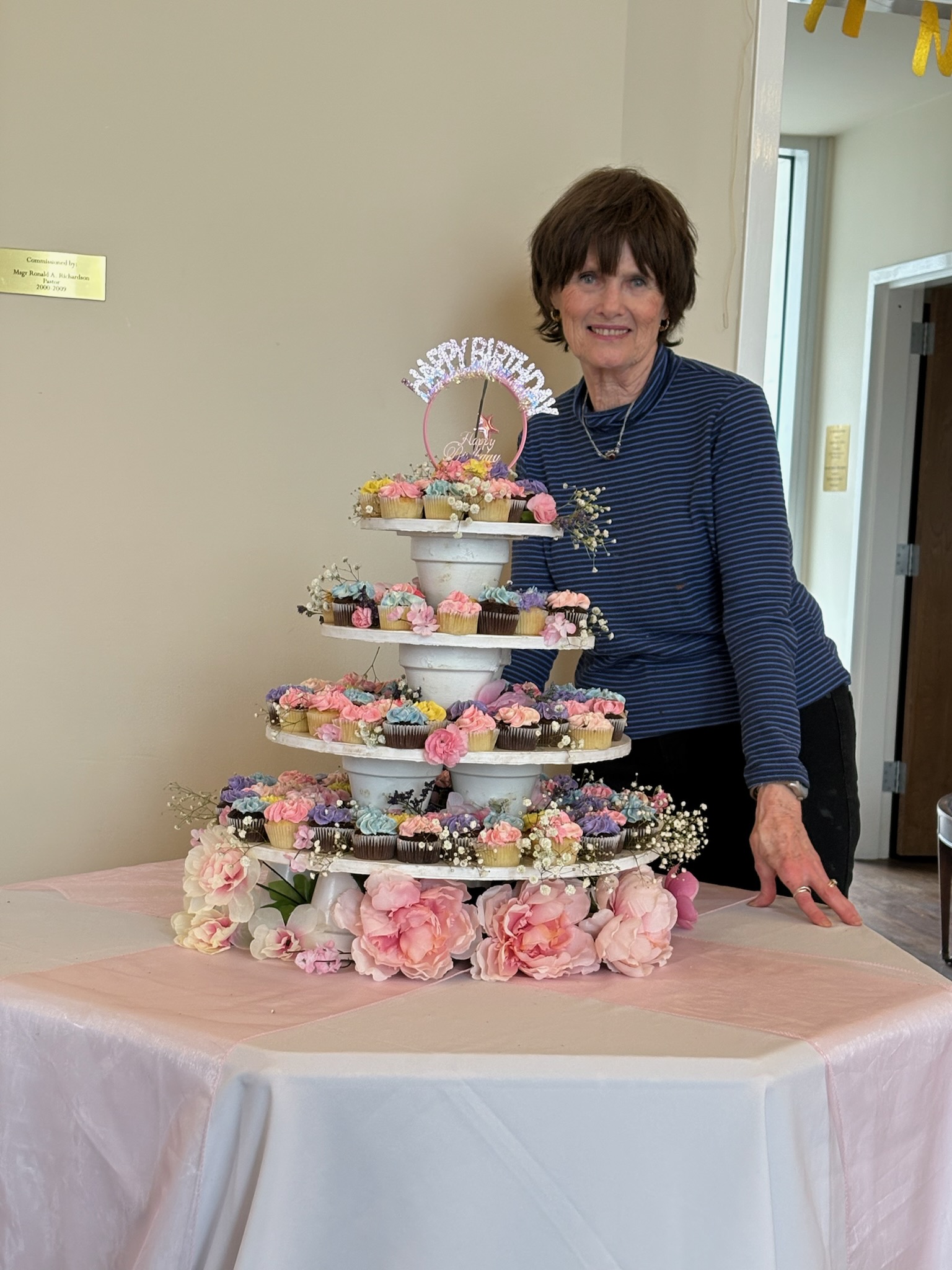 Kathy Burton beside a tiered display of decorated cupcakes