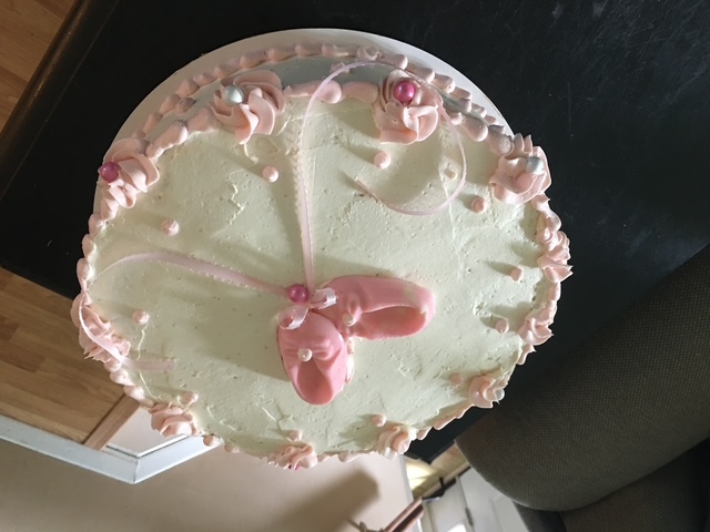 Ivory celebration cake with pink piped details and a bow