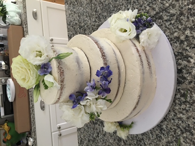 Three-tier semi-naked cake with white and purple flowers