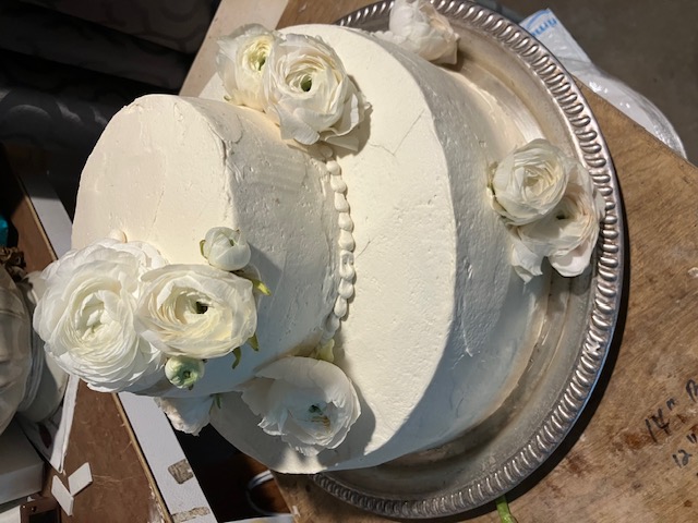 Two-tier white cake finished with white roses